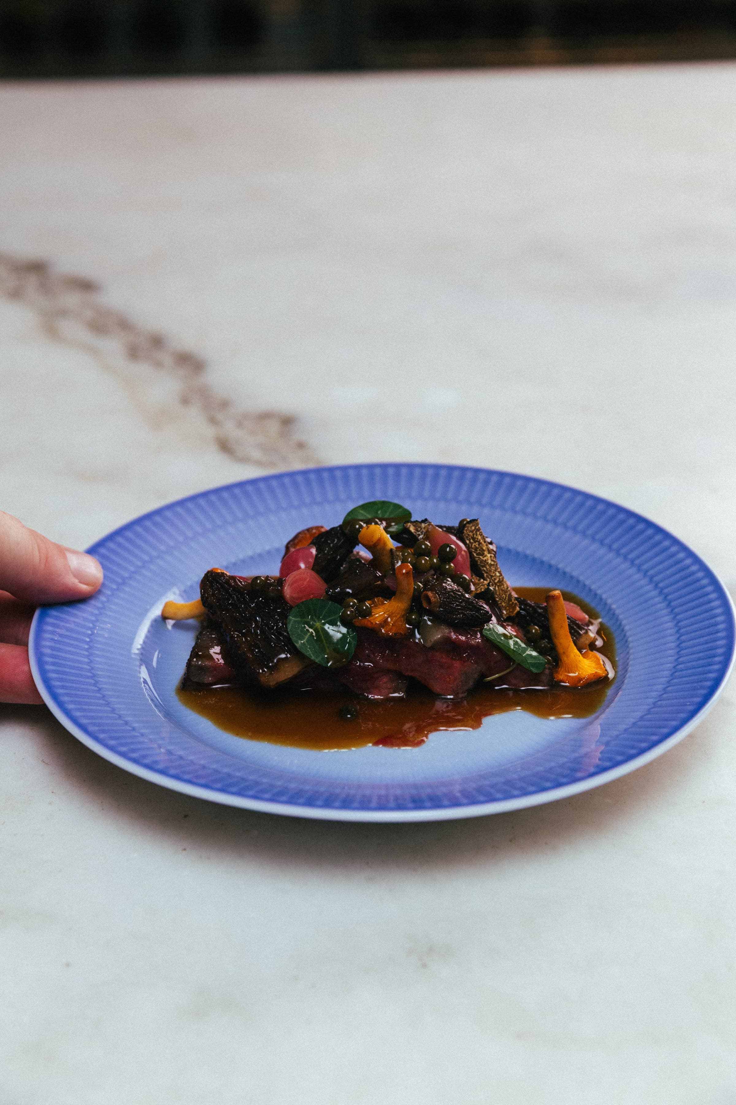 Chef carrying a plate through the MALMA dining room